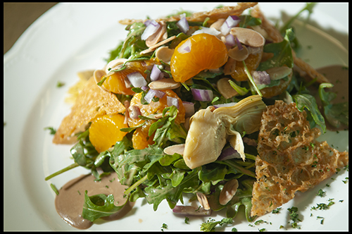 Arugula Salad with Artichoke Hearts, Mandarine Oranges, Red Onions, Almond Slivers and a Parmesan Crisp tossed in a Honey-Balsamic Vinaigrette
